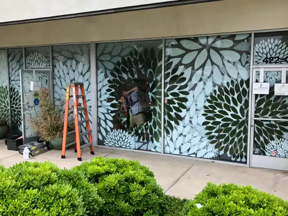 Storefront glass carrying a large-scale decorative privacy pattern.