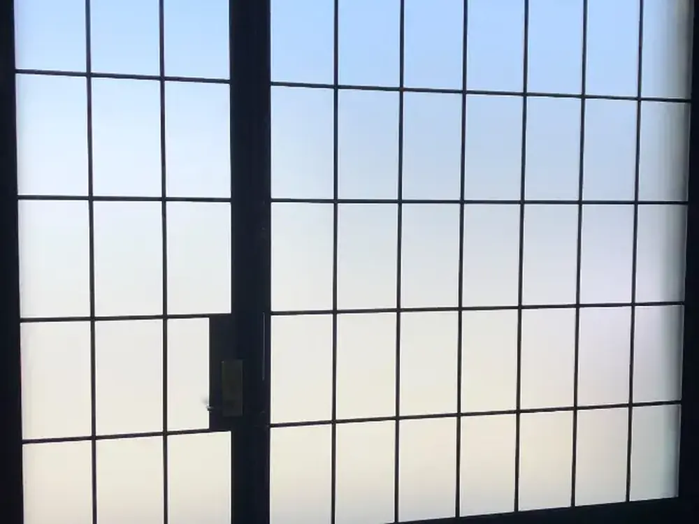 A steel grid window fully frosted, glowing with daylight but giving nothing away.