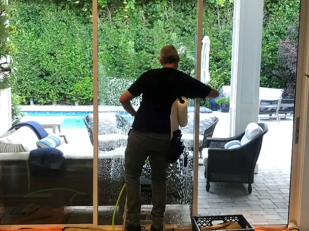 Film being applied wet to a full-height slider, squeegeed pane by pane.